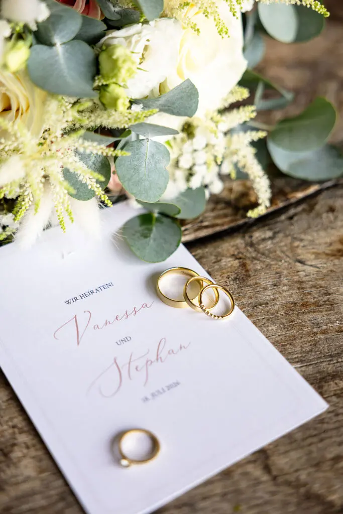 Hochzeitsdetails – Eheringe, Einladung und Brautstrauß Eheringe, Hochzeitseinladung und Brautstrauß als Detailaufnahme bei einer Hochzeit