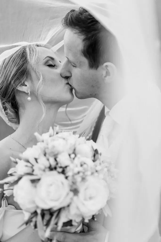 Brautpaar beim Kuss auf der Turracher Höhe Braut und Bräutigam küssen sich bei ihrer Hochzeit auf der Turracher Höhe, mit Blumenstrauß und Schleier